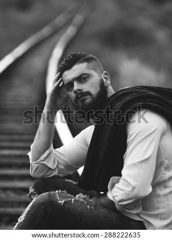 portrait of a bearded young man on a railway line black and white photography