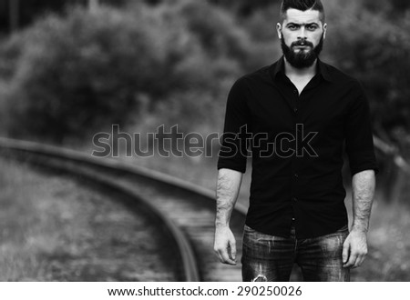 young beautiful young man standing on a railway line black and white photography