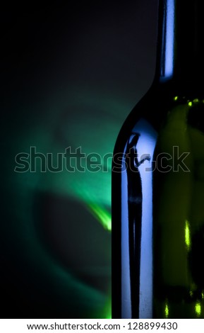 Bottle of wine on the dark background. A slim woman in door space is seen in the reflection. Good as a background with a copy-space.