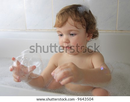 A child playing with soap foam in a bathtub.