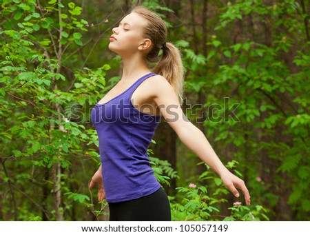 Young beautiful woman with closed eyes doing yoga meditation in forest outdoors