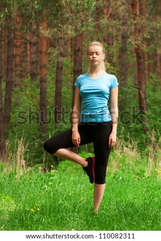 Young beautiful woman doing yoga meditation exercise in forest outdoors