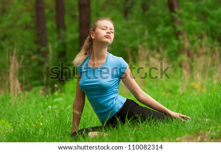 Young beautiful woman doing yoga meditation exercise in forest outdoors