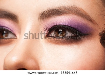 Close-up image of young asian woman eye with bright violet makeup