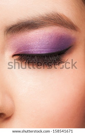 Close-up image of young asian woman eye with bright violet makeup