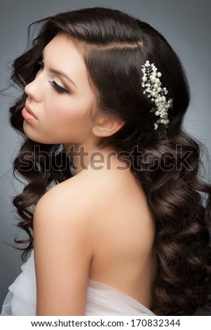 Portrait of a pretty young woman with a beautiful bridal hairstyle and makeup. Brunette with long wavy hair