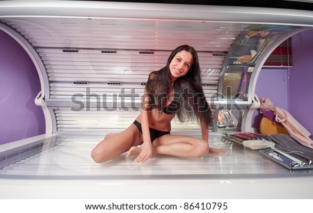 Young beautiful woman with slim body in tanning bed