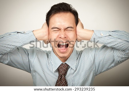 stressed  asian man covering closed ears looking at you, don\'t want to listen or headache.