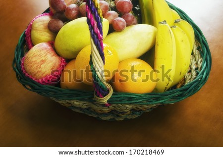Gift fruit basket filled with grapes, apples, mangoes, bananas, and oranges