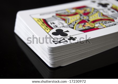 Deck of cards against black background; King of Clubs right side up