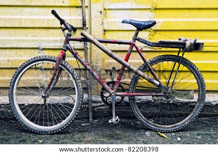 Rusty mountain bike leaning on yellow wall