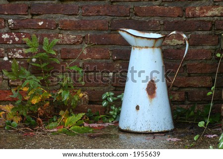 old rusty watering-can against an old garden-wall