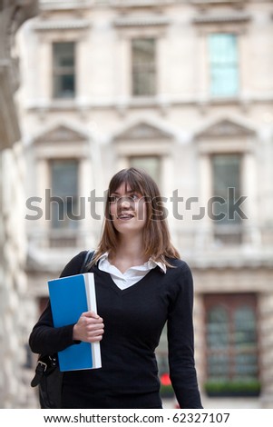 Master student outdoors holding a folder and smiling
