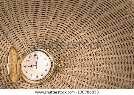 Antique pocket watch on a textured woven straw. Close-up.