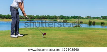 Man simulates play golf. With the stick on the green field.