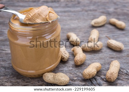Jar of peanut butter with nuts. On wooden texture.