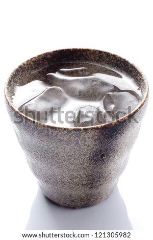 Distilled spirit into the pottery cup on white background
