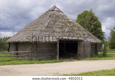 Rural road with old shed with straw roof.