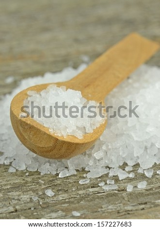 Natural sea salt crystals with wooden spoon on rustic table