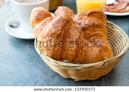 Breakfast with coffee and croissants in a basket on table