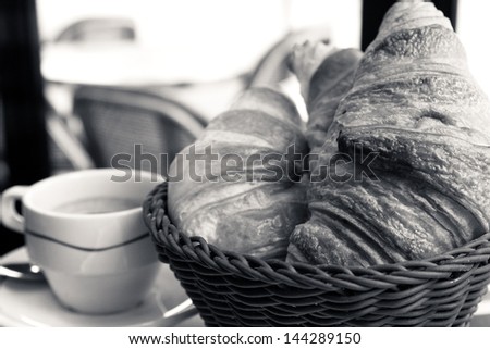 Breakfast with coffee and croissants in a basket on table