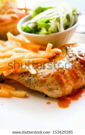 Chicken with sauce and golden French fries potatoes