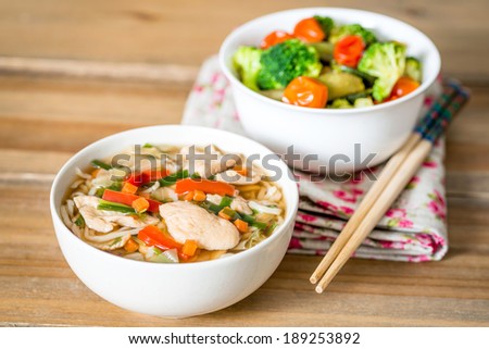Bowls of Asian soup noodles and vegetables with Chopstick