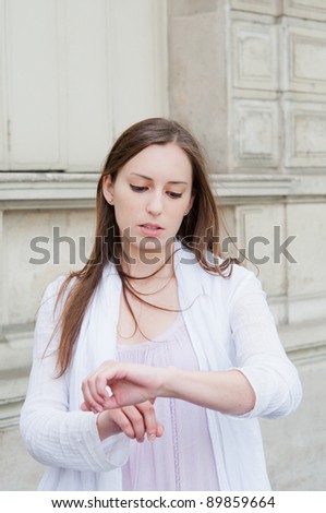 beautiful young woman checking the time on her wrist watch in the streets of Paris