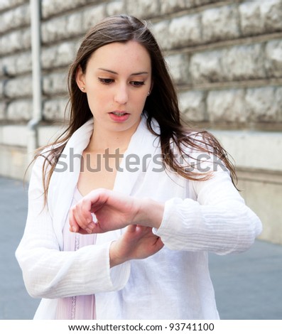 beautiful young woman checking the time on her wrist watch in the streets of Paris