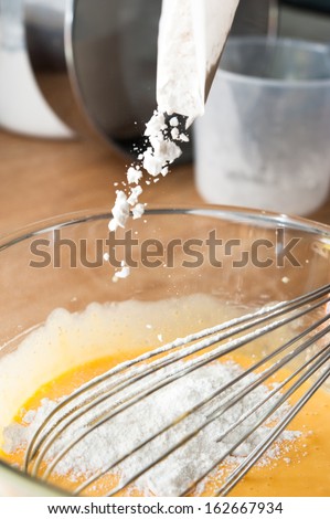 Adding flour into mixed yolk eggs and sugar prepare for baking c