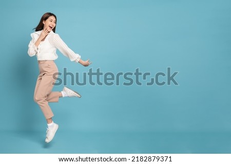 Young beautiful asian woman with smart casual cloth jumping and smiling with excitement looking at copy space isolated on blue background Сток-фото © 