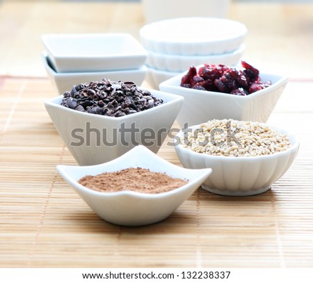 detail photo of healthy ingredients; cacao nibs, cacao powder, cranberries, buckwheat