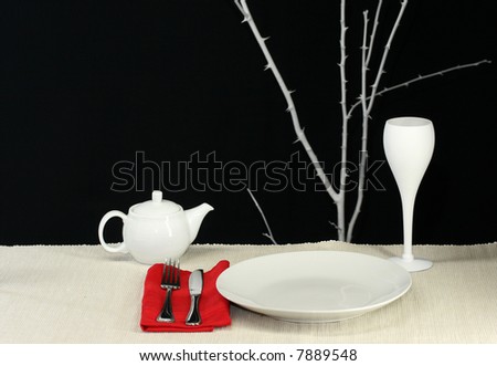 An elegant modern table set for dinner in black and white with red accent