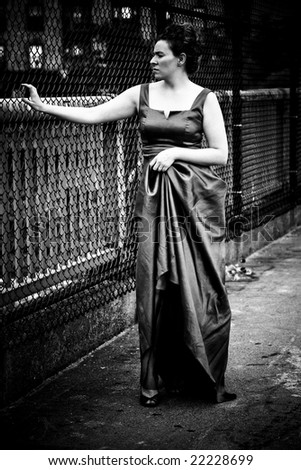 A young woman in an evening gown in a dirty urban setting