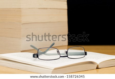 Pile of books with glasses on open book