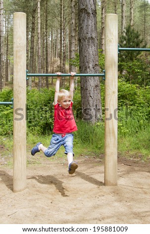 Cute blond boy swinging by his arms from a high bar