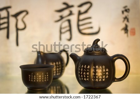 Black matte Chinese tea set with teapot and cup against a background of chinese characters and stamp