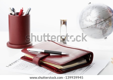 Luxury leather personal organizer with pen on white office desk. Shallow focus.