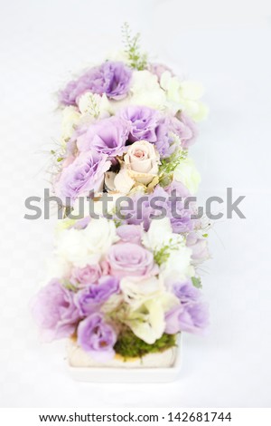 Professionally prepared decorative spring flower arrangement on reception wedding table. Shallow focus, white linen background.