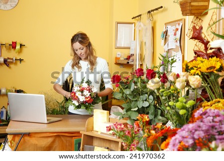 Portrait of mature florist holding a bouquet of flowers in flower shop. Online shopping.