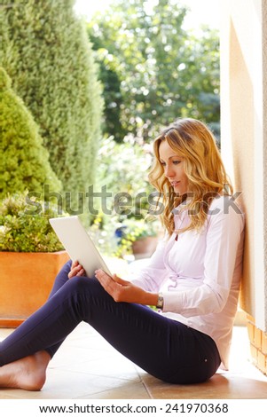 Portrait of happy blogger writing her blog at laptop while sitting at garden at home.