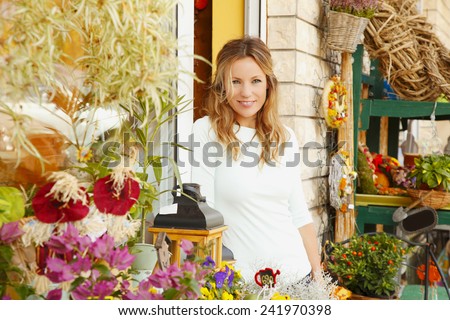 Portrait of middle age flower shop owner standing in front of flower shop. Small business.