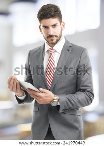 Executive young businessman holding digital tablet while standing at office.