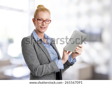 Portrait of executive business woman standing at office while using digital tablet.