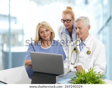 Portrait of medical team working at laptop and consulting.  Doctors and medical assistant sitting in front of computer and checking the result of medical test at private clinic.