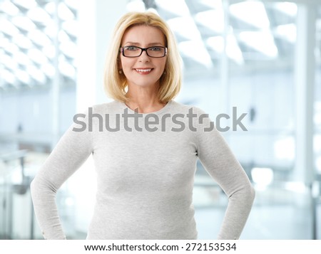 Businesswoman portrait. Close-up of middle age businesswoman standing at meeting room while looking at camera and smiling.