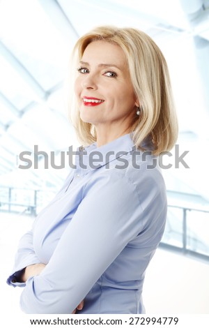Waist up portrait of beautiful middle age businesswoman standing at office while looking at camera.