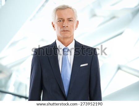 Image of senior bank manager standing at office and looking at camera. Business person.