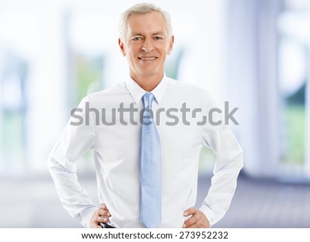 Image of senior broker standing at office while looking at camera and smiling. Business people.