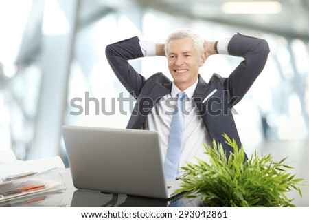 Portrait of senior director sitting at office in front of laptop. Businessman sits back and relaxing.